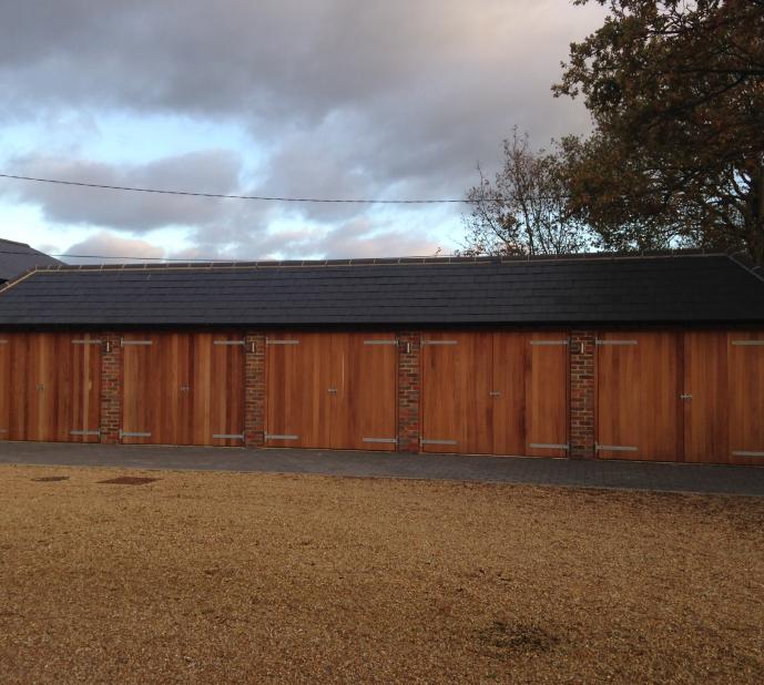 Block of wooden fronted garages, with slate roofing. 